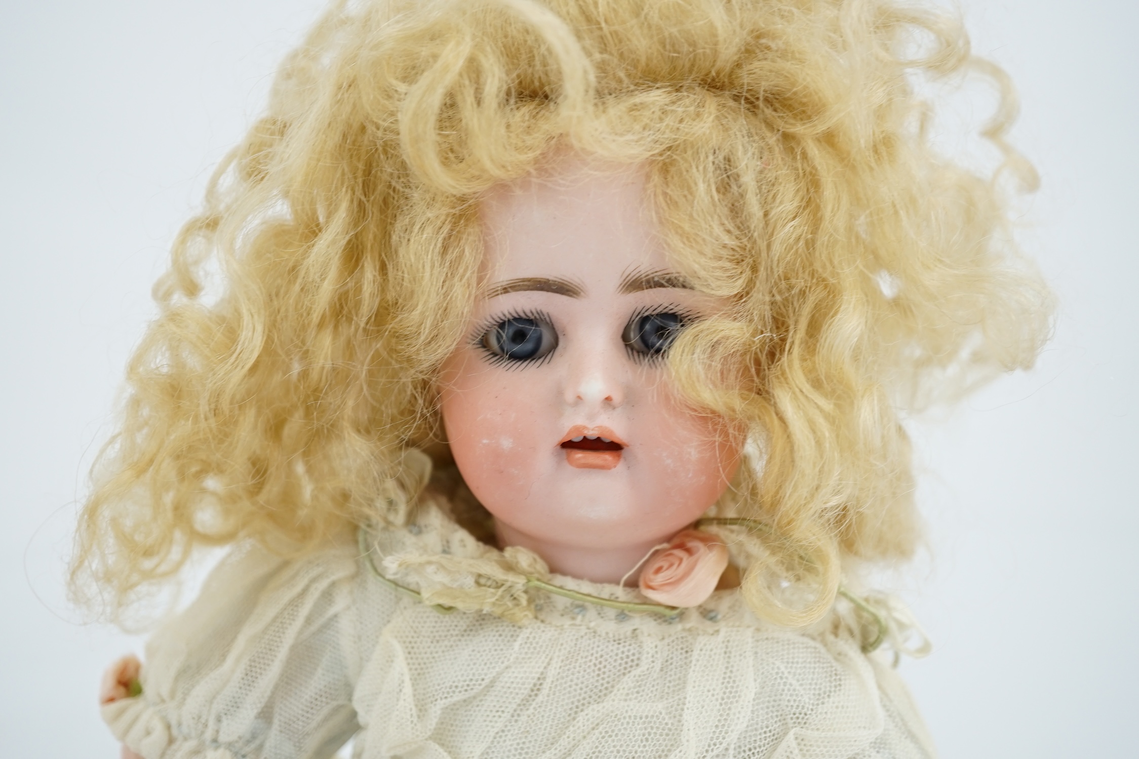 A Kammer & Reinhart / S & H bisque head doll, pierced ears, vintage clothes, one finger missing, slight rub to robe, 34cm